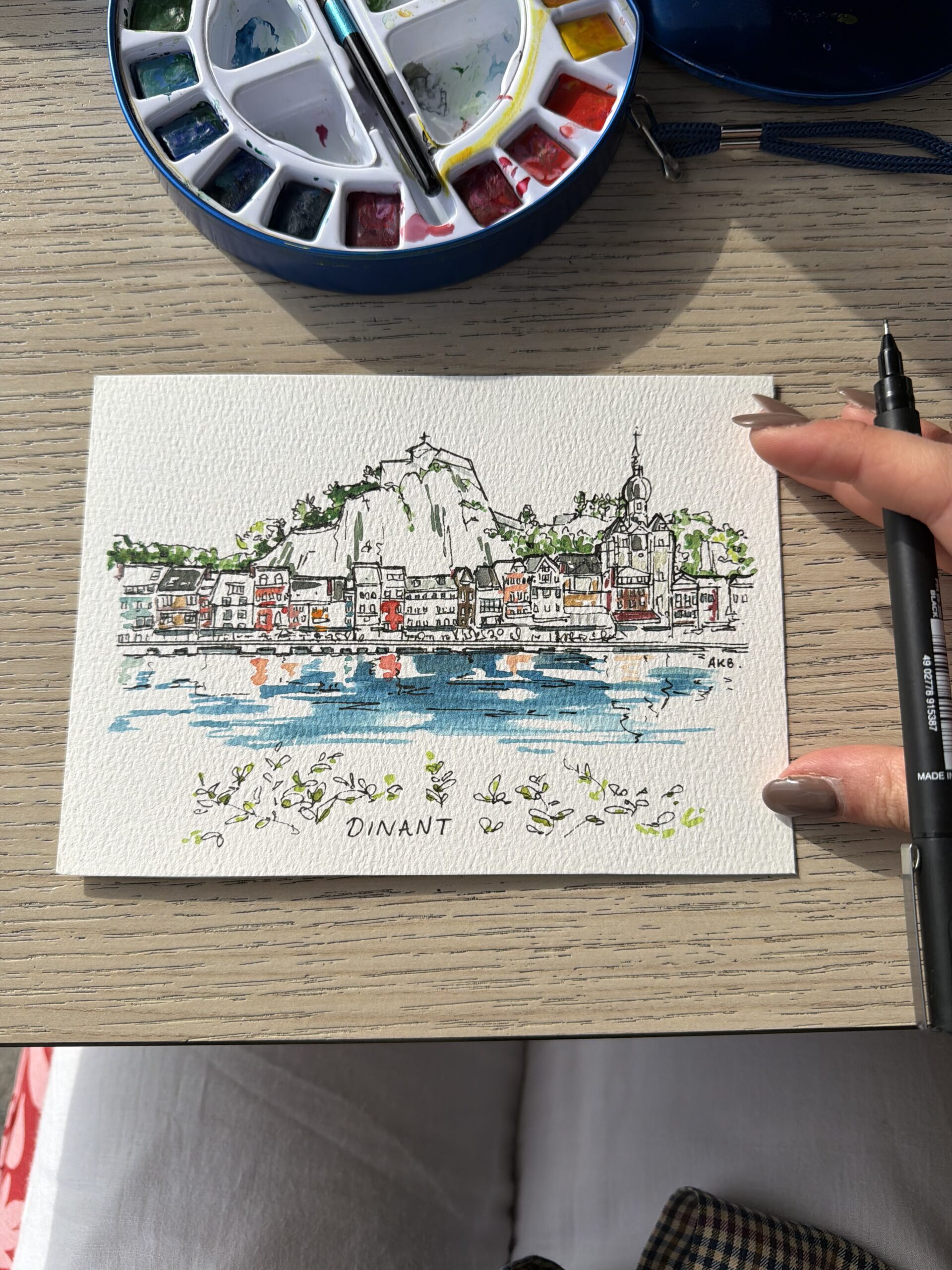 Hand-painted waterfront architectural illustration in ink and watercolour with a palette and brushes