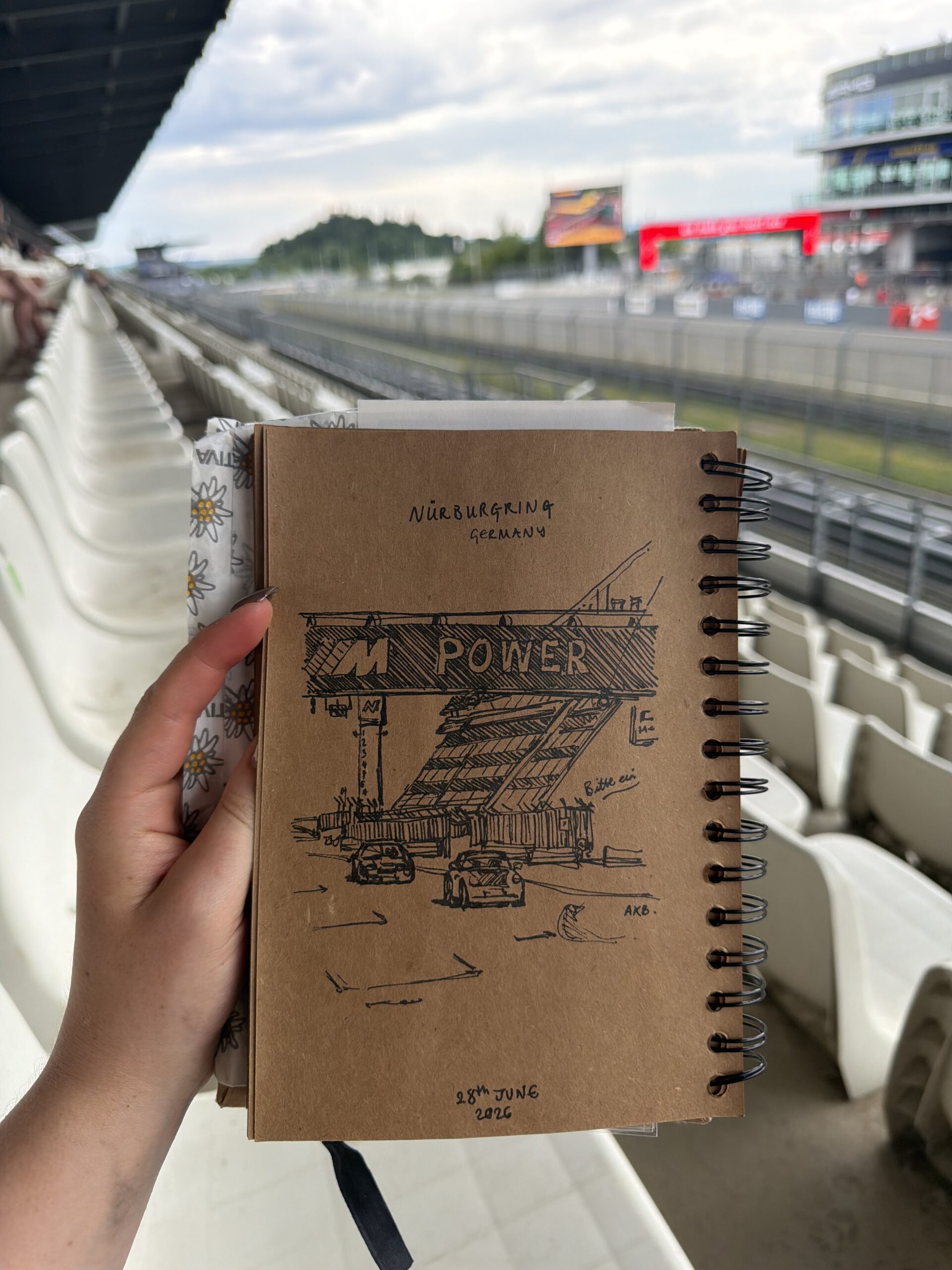 Hand holding a spiral-bound sketchbook with an architectural ink drawing